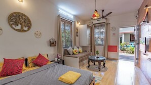 A room with a bed, a sofa, a small table, and a ceiling fan.