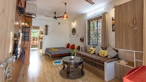 A compact living space with a bed, sofa, dining table, and a kitchenette area.