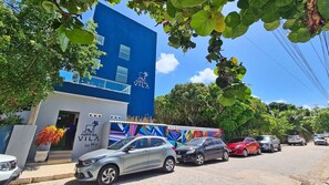 A building with a blue facade, a colorful mural, and parked cars on the street. - Porto Sol Vila By Aft (Ipojuca)