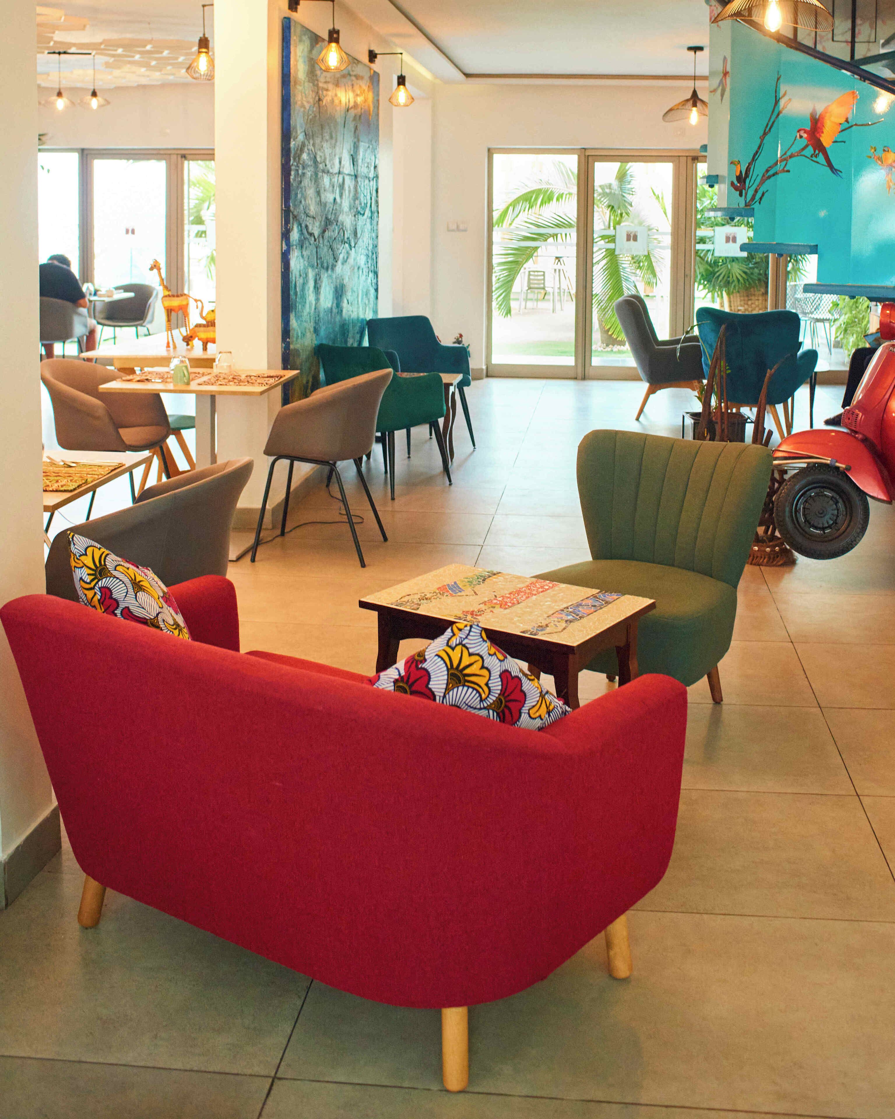 A spacious indoor area with multiple seating options including a red sofa, green armchairs, and a dining table with chairs.