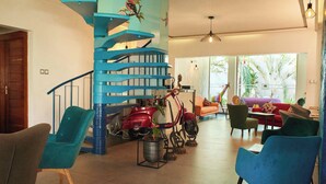 A modern interior with a spiral staircase, seating area, and a red scooter. - LE KARE EBENE (Cotonou)