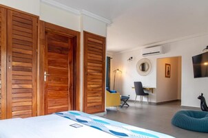 Una camera d'albergo con un letto, un armadio in legno, una scrivania, una sedia e uno specchio rotondo appeso al muro.