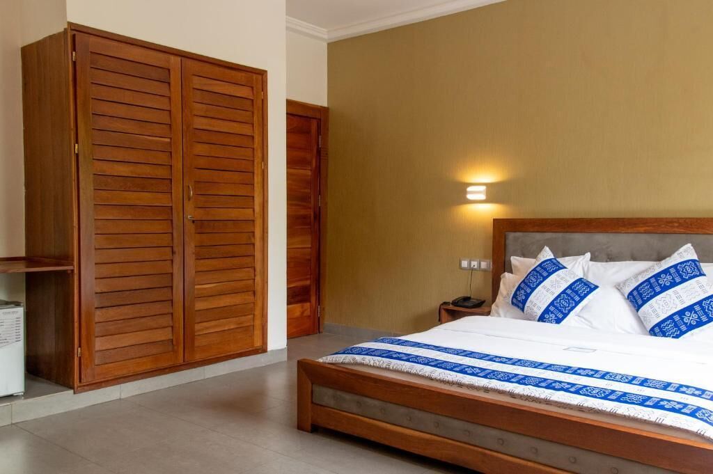Un dormitorio con cama, armario de madera y mesita de noche con lámpara.