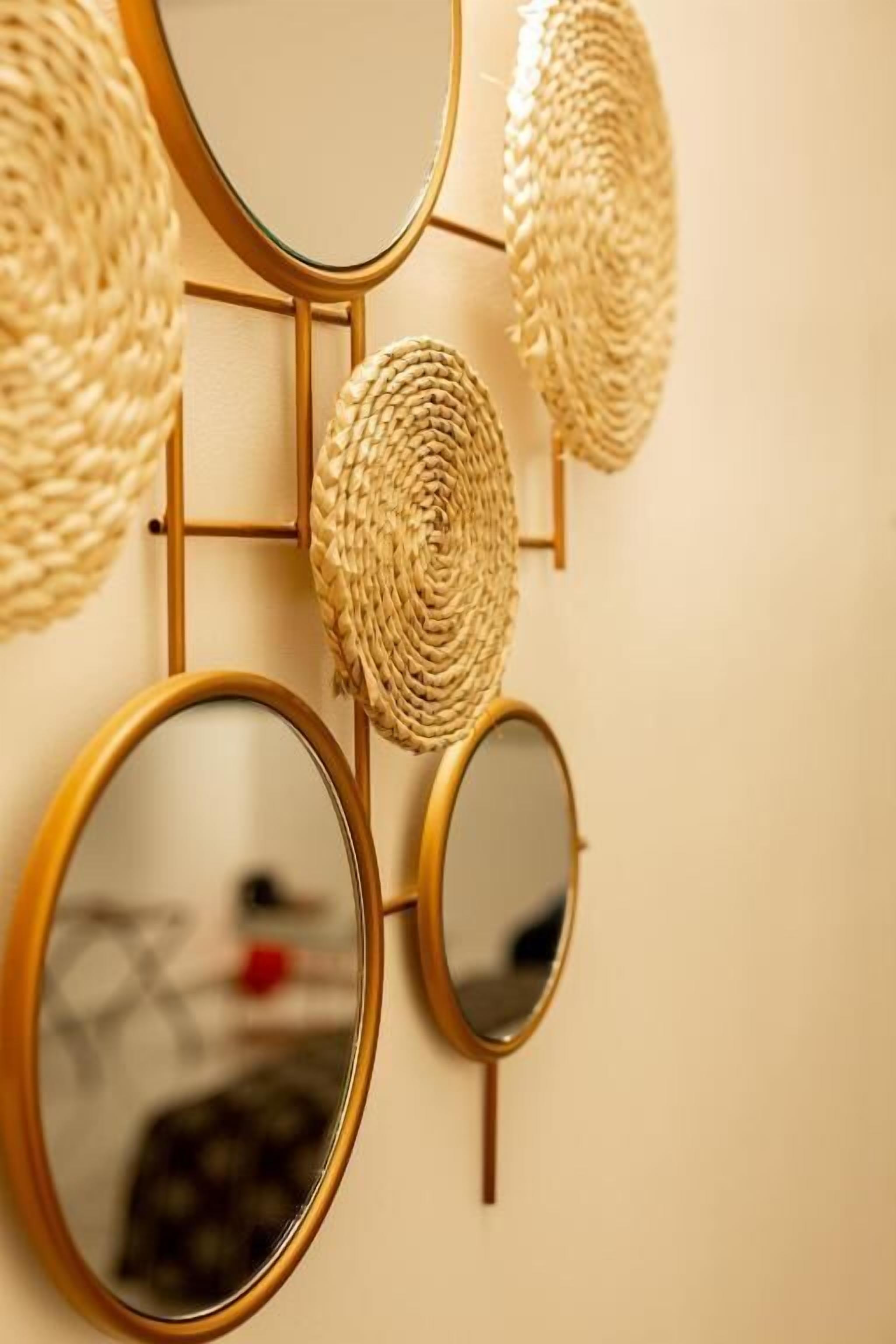 A wall-mounted mirror with a gold frame and a woven basket.