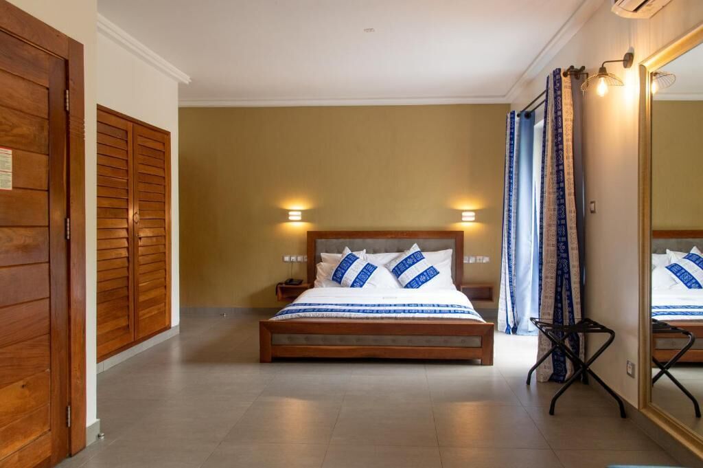 A bedroom with a wooden bed, two bedside lamps, a nightstand, and a mirror.