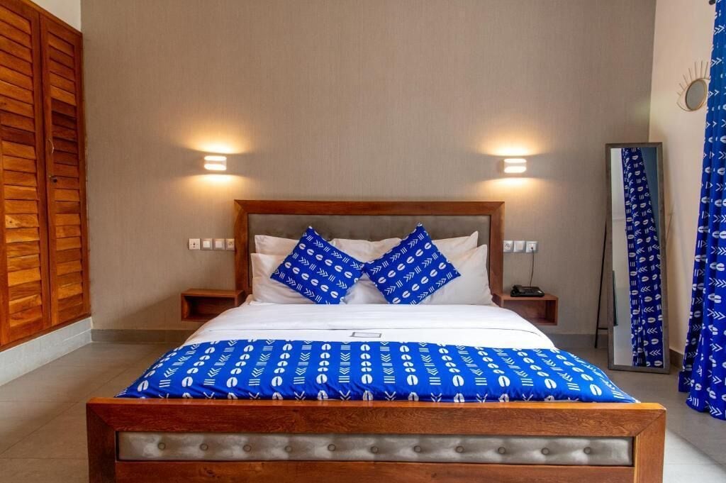 Una cama con estructura de madera, dos mesitas de noche y un espejo.