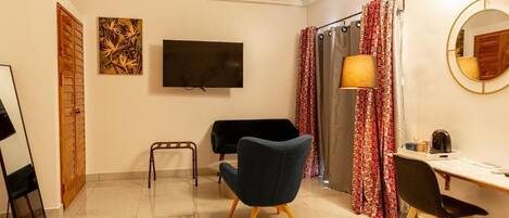 Une chambre dotée d’une télévision à écran plat, d’un bureau avec une chaise, d’un canapé et d’un lit.