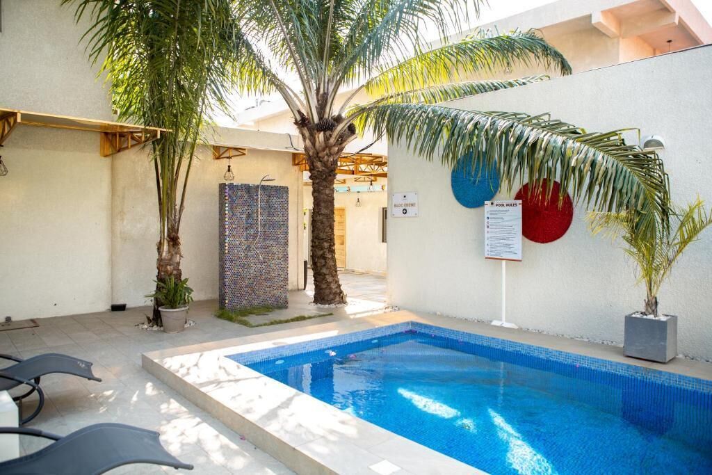 A swimming pool with a tiled deck, palm trees, and a wall with a sign.