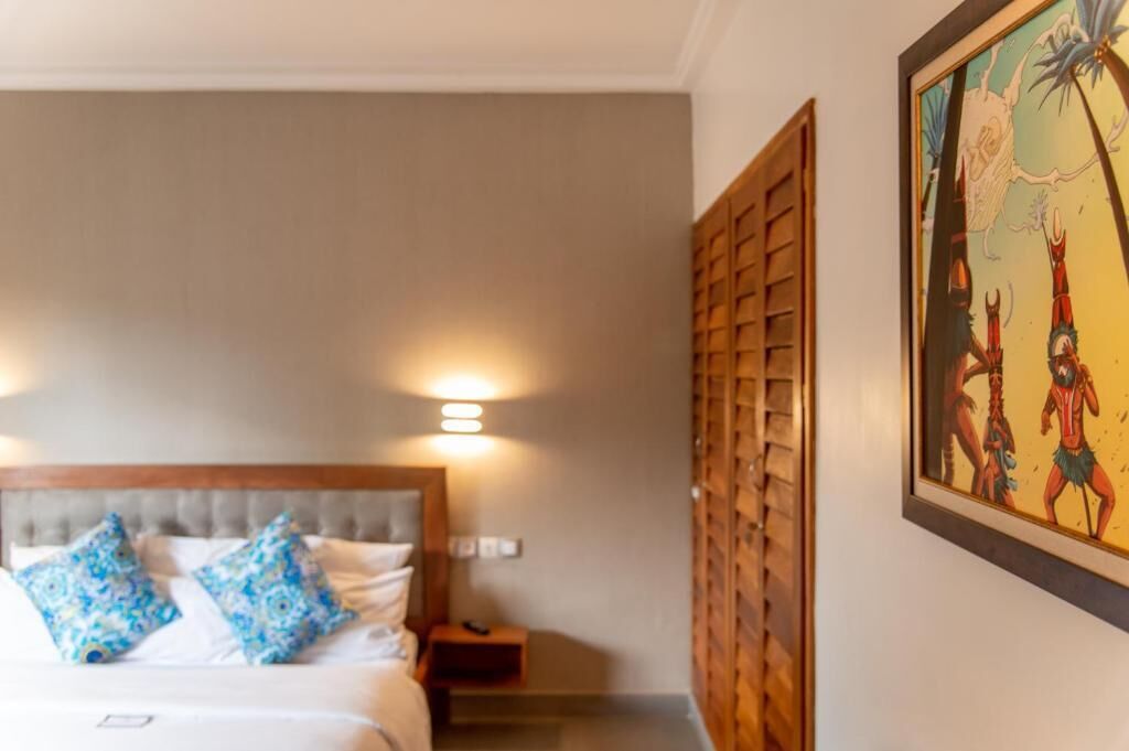 A hotel room with a bed, bedside lamps, a nightstand, and a wall-mounted artwork.