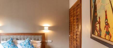 A hotel room with a bed, bedside lamps, a nightstand, and a wall-mounted artwork.
