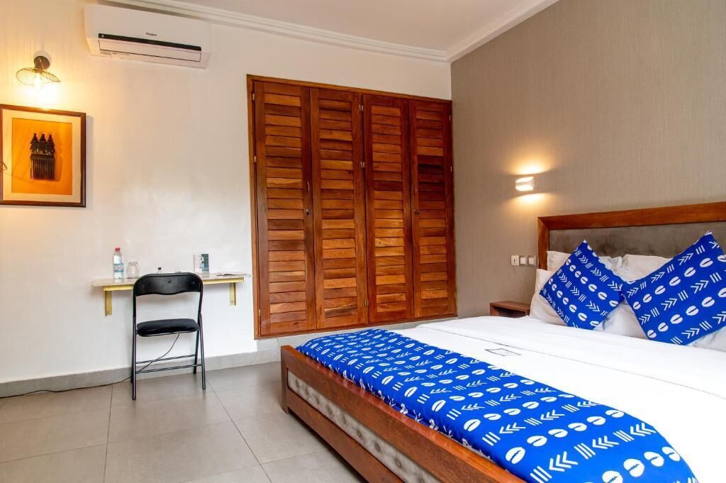 Un dormitorio con cama, armario de madera, escritorio con silla y aire acondicionado instalado en la pared.