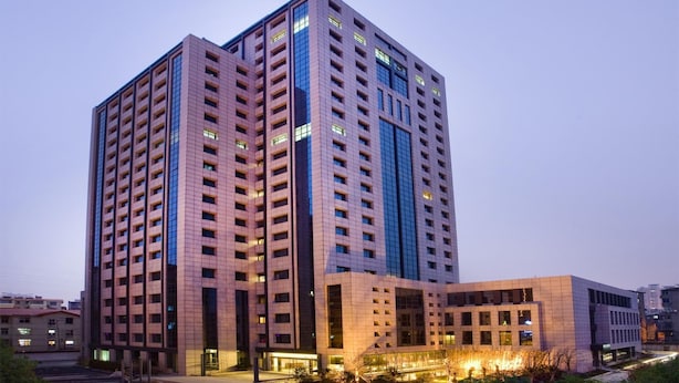 A multi-story building with a modern architectural design, featuring a prominent vertical glass facade and a series of balconies. - Nanchang Ssaw Hotel (Nanchang)
