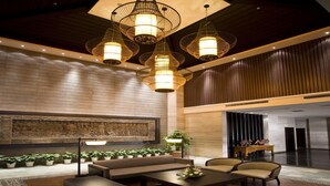 A lobby with a seating area, a large wall with a relief sculpture, and multiple hanging light fixtures. - Nanchang Ssaw Hotel (Nanchang)