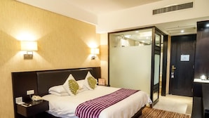 A hotel room with a bed, nightstand, lamp, and a mirror. - Nanchang Ssaw Hotel (Nanchang)