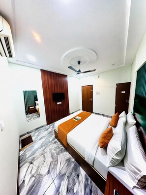 A hotel room with a bed, a ceiling fan, a TV, and a marble floor. - P2 Hotel (Indore)