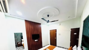 Ein Hotelzimmer mit Bett, Deckenventilator, Fernseher und einer Wand aus Holzverkleidung.