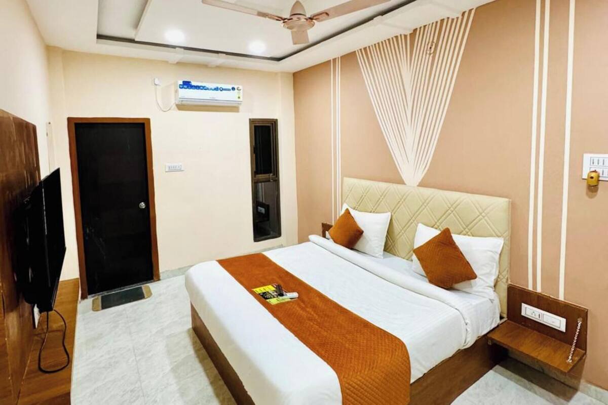 A hotel room with a bed, a ceiling fan, a TV, and a door.