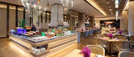 A hotel dining area with a buffet, tables set for dining, and a bar area.