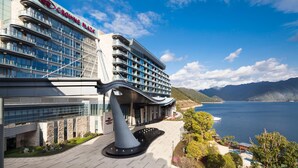 A modern hotel with a prominent 'Crowne Plaza' sign, a waterfront view, and a landscaped entrance area. - Crowne Plaza Hangzhou Thousand Island Lake (Hangzhou)