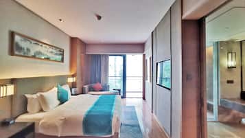 A hotel room with a large bed, bedside tables, a painting on the wall, and a view through an open door.