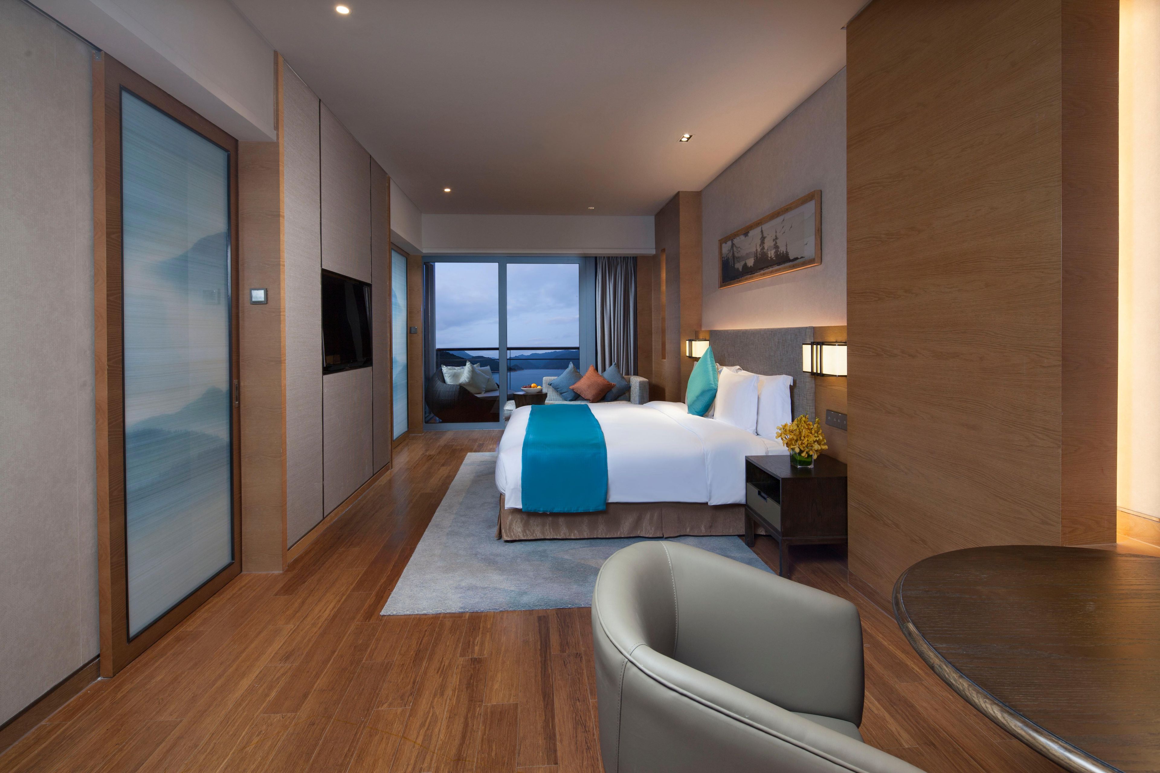 Een hotelkamer met een bed, bureau, stoel en uitzicht op het landschap.