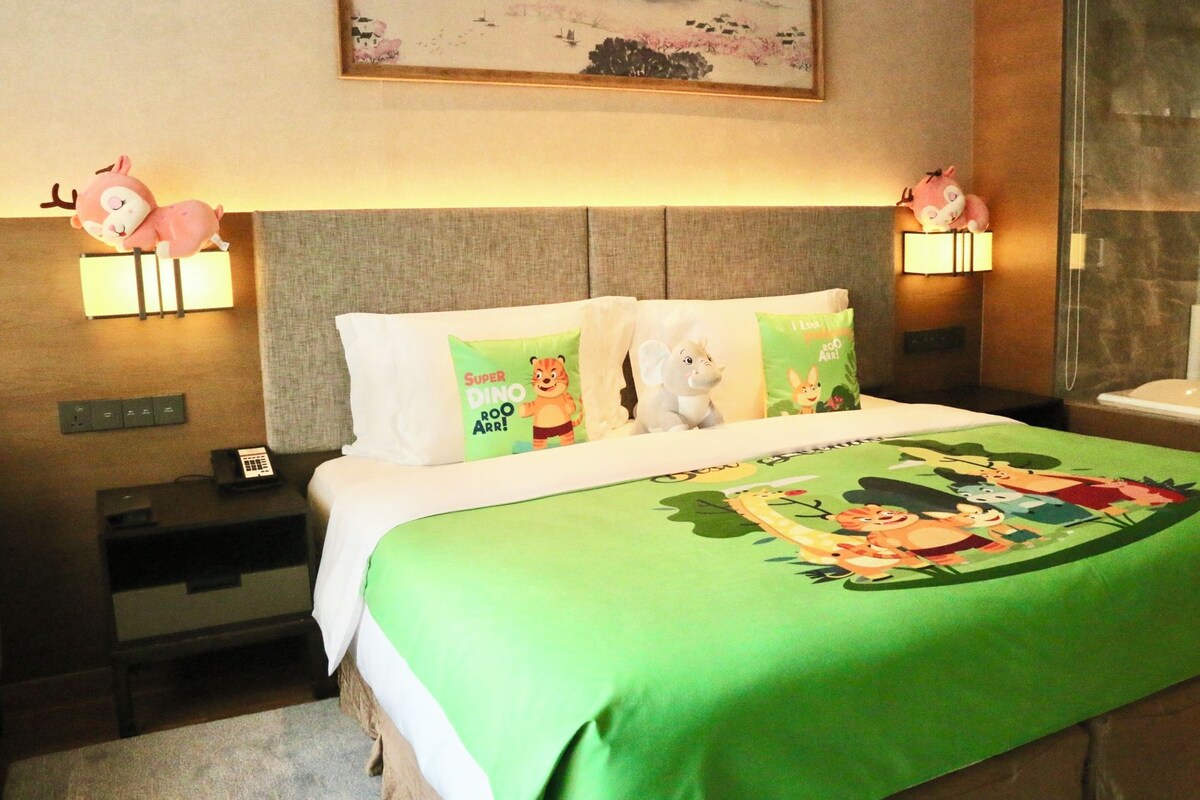 Quarto de hotel com cama, mesas de cabeceira, telefone, almofadas decorativas e luminárias fixadas na parede.