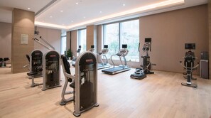 Un gimnasio moderno con máquinas de cardio, estaciones de pesas y ventanas amplias.