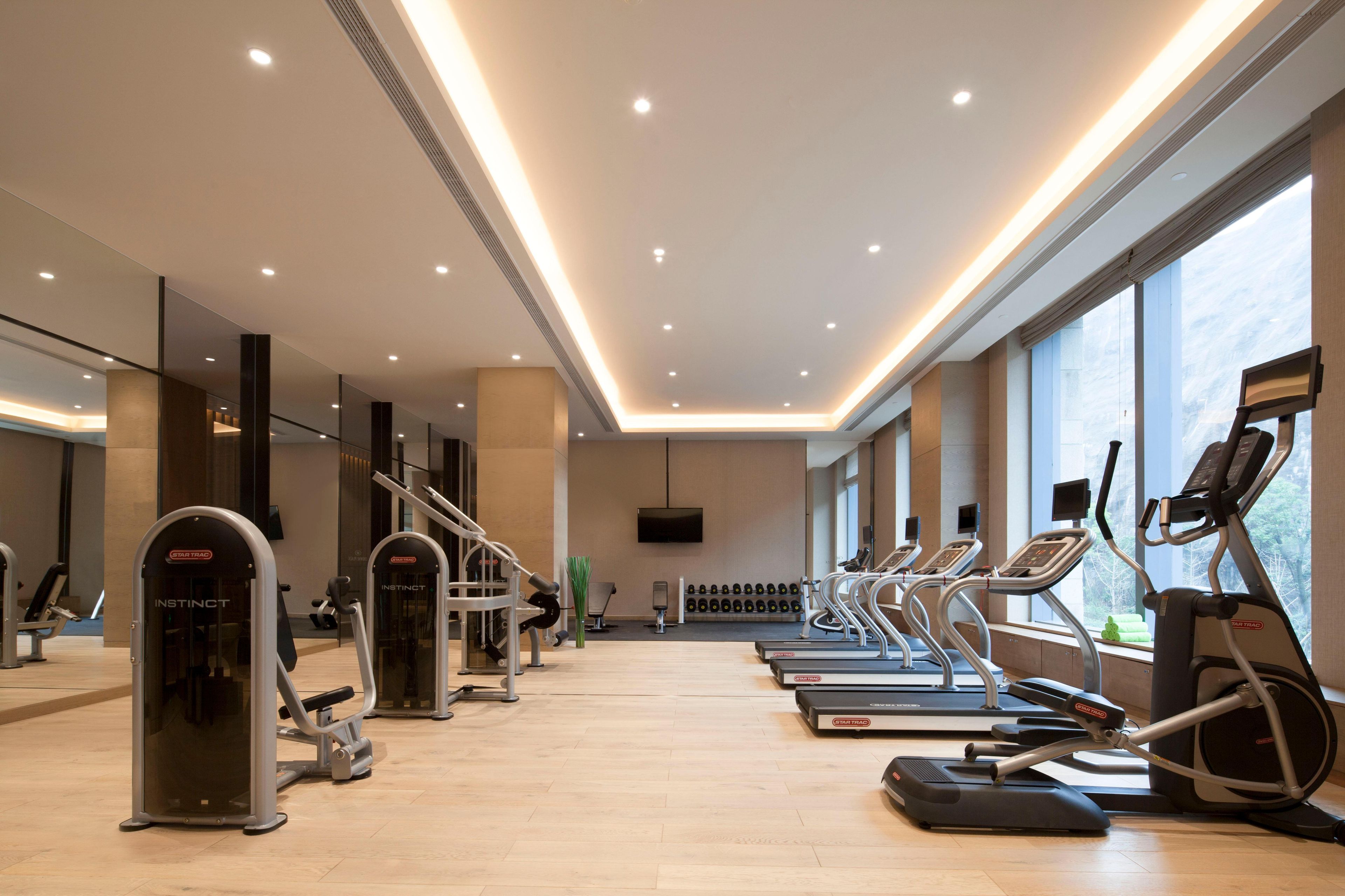 Un gimnasio con cintas de correr, elípticas y máquinas de pesas.