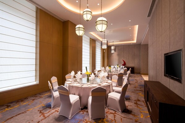 A conference room with round tables, chairs, and a flat-screen TV. - Crowne Plaza Hangzhou Thousand Island Lake (Hangzhou)