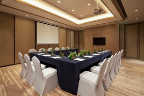 A conference room with a long table, white chairs, a projector screen, and a flat-screen TV. - Crowne Plaza Hangzhou Thousand Island Lake (Hangzhou)