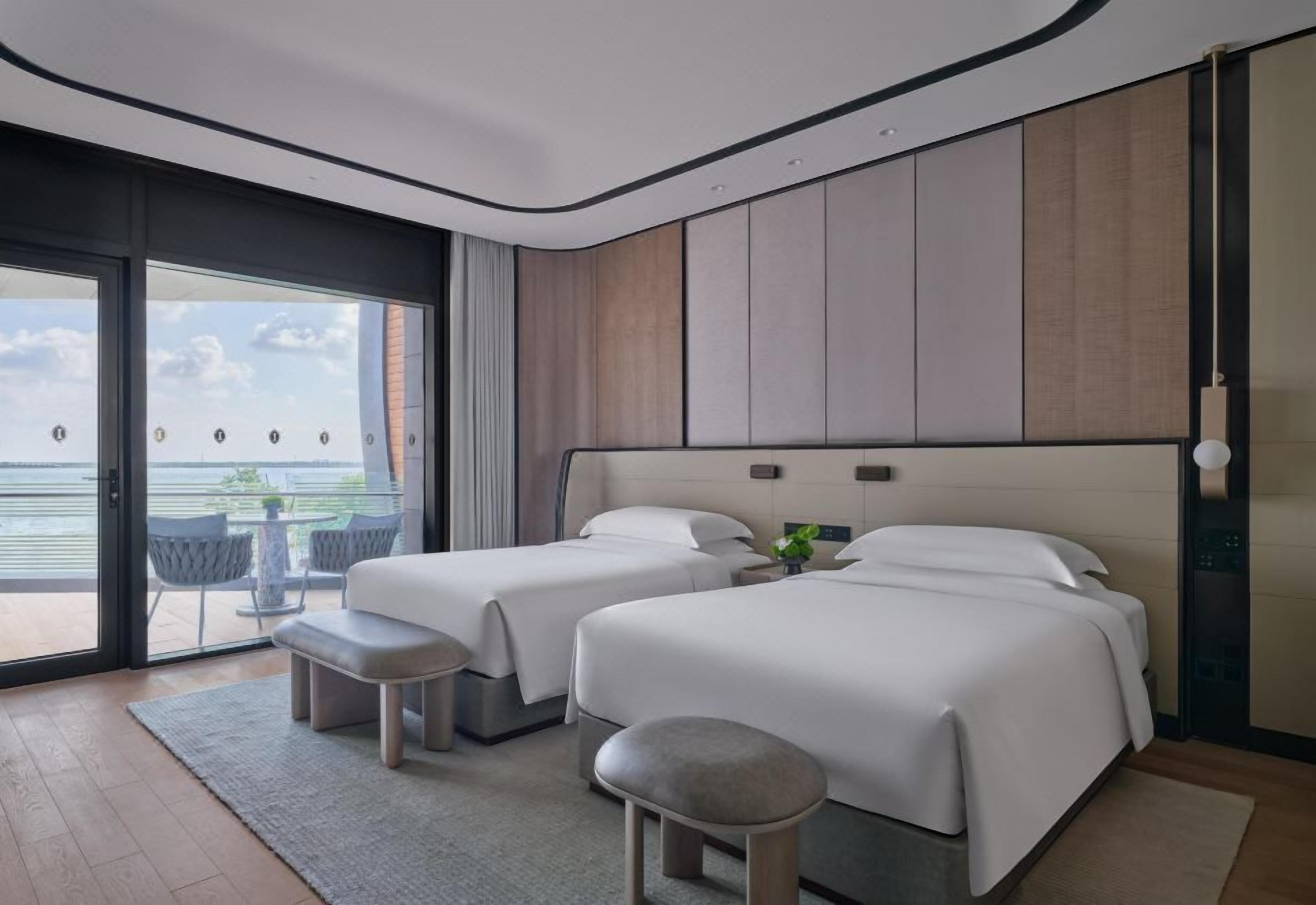 Ein Hotelzimmer mit zwei Betten, einem Balkon und Blick auf das Wasser.
