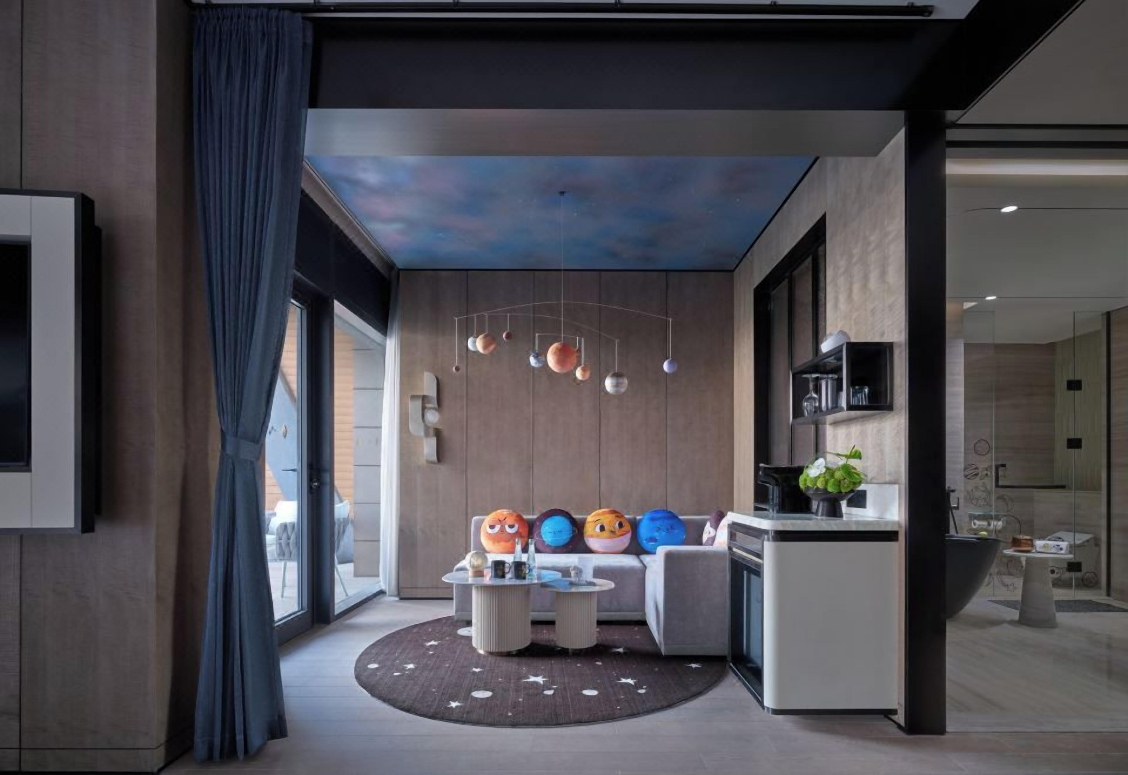 A modern interior with a seating area, a kitchen, and a ceiling with a celestial design.