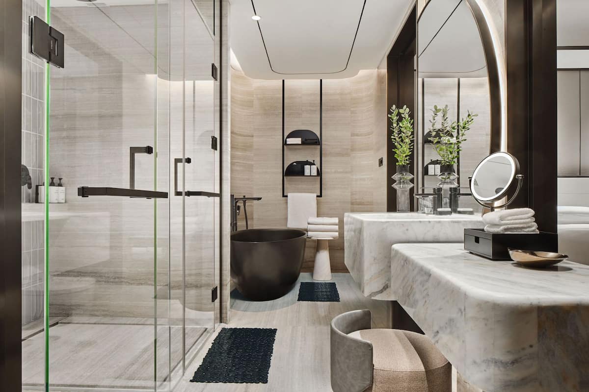 A modern bathroom with a glass-enclosed shower, a large bathtub, and a marble vanity with a mirror.