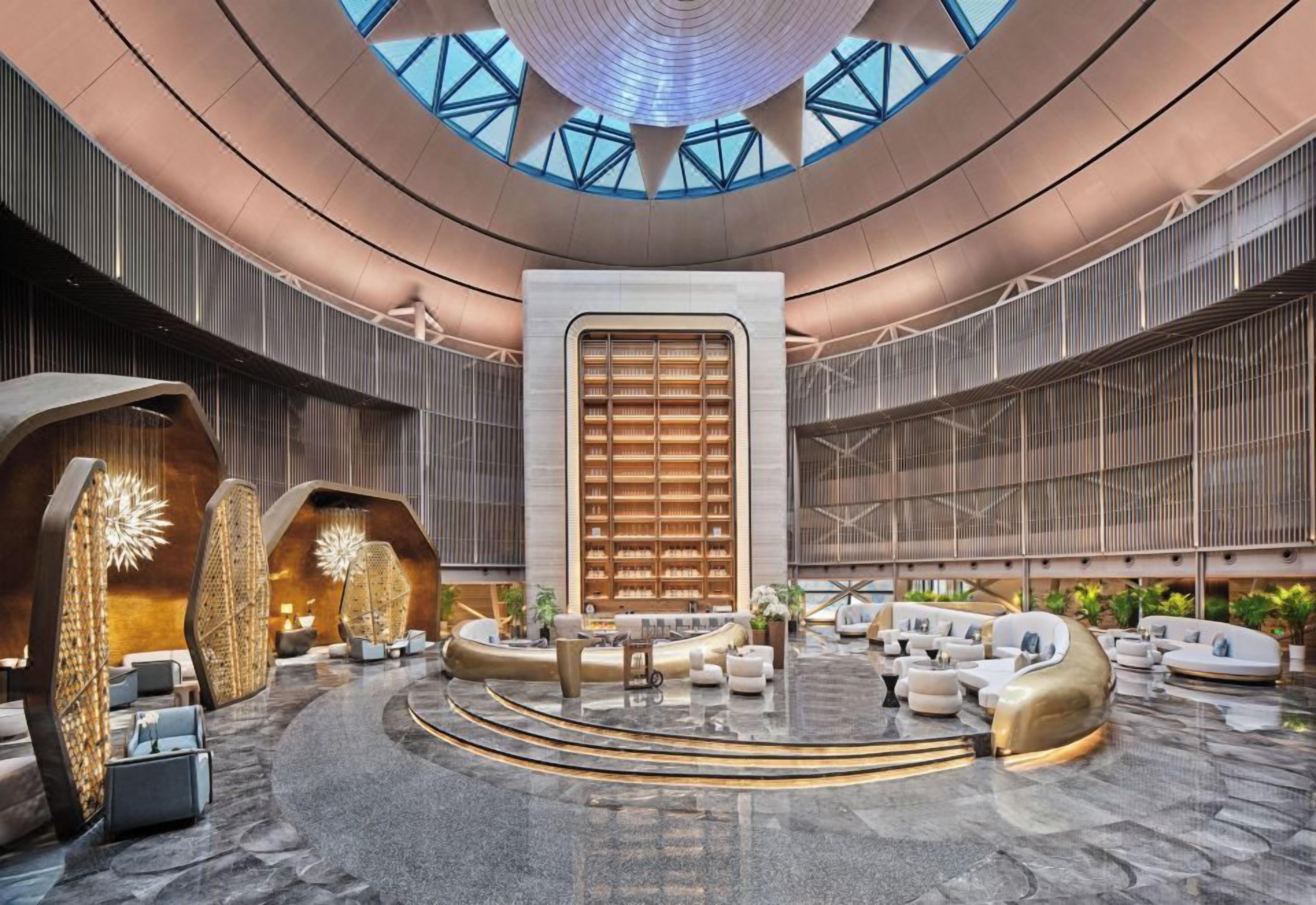 A spacious lobby with a central seating area, a large bookshelf, and a high ceiling with skylights.