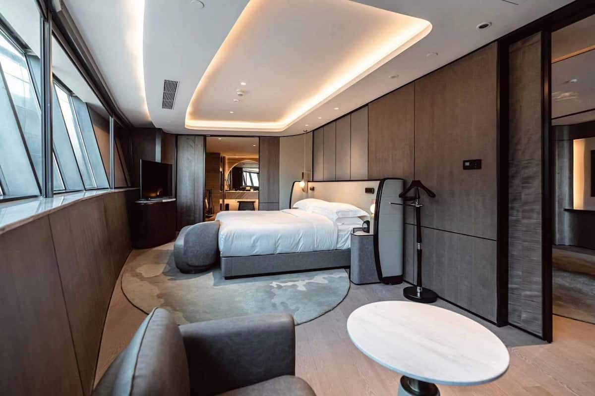 A modern bedroom with a bed, bedside tables, a floor lamp, and a round table.