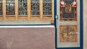 Una porta in legno tradizionale con elaborate decorazioni a griglia e un pannello decorativo.