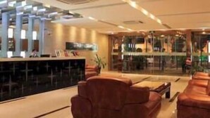 A modern lobby with a reception desk, leather seating, and a large glass window. - Ji Hotel (Suzhou)