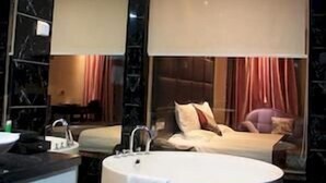 A modern bathroom with a large bathtub, a sink, and a mirror. - Ji Hotel (Suzhou)