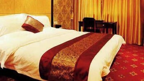 A hotel room with a large bed, a wooden headboard, a red carpet, and a curtain with a vertical pattern. - Ji Hotel (Suzhou)