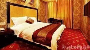 A hotel room with a large bed, a nightstand, a chair, and a patterned carpet. - Ji Hotel (Suzhou)