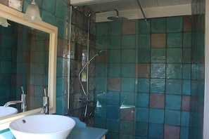 A bathroom with a sink, mirror, and shower.