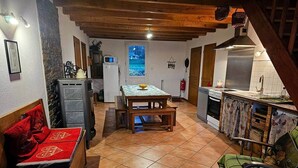 A cozy kitchen with a dining table, a refrigerator, and a stove. - La Ferme - House with terrace (Mélisey)