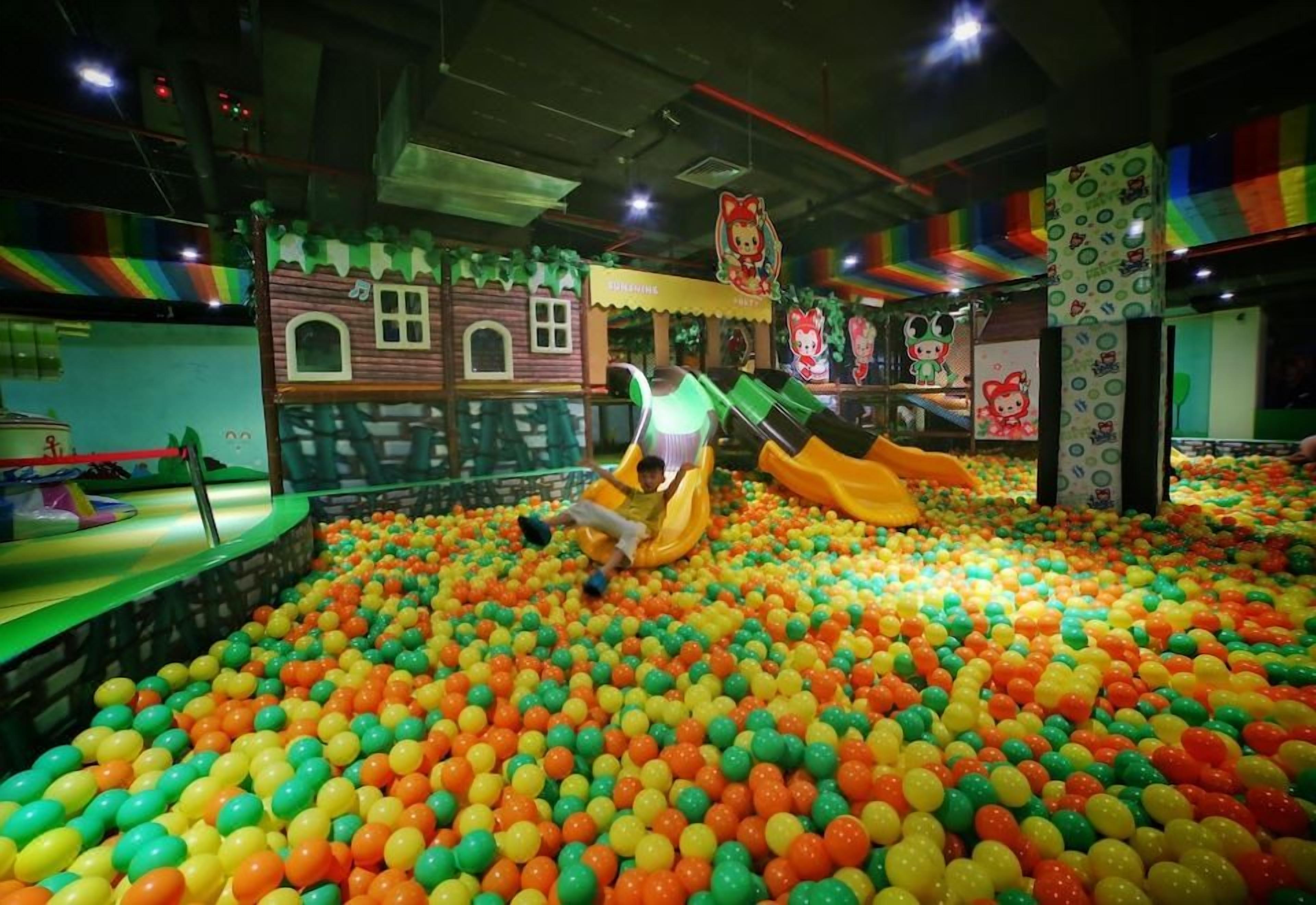 Zona de juegos con piscina de pelotas y toboganes.