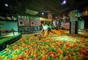 Zona de juegos con piscina de pelotas y toboganes.