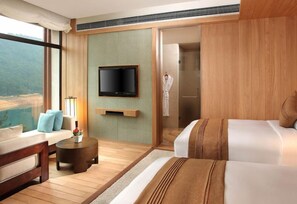 A hotel room with a large window, a flat-screen TV, a sofa, a bed, a small round table, and a walk-in shower. - Qiandaohu Liberty Interworld Palace (Hangzhou)