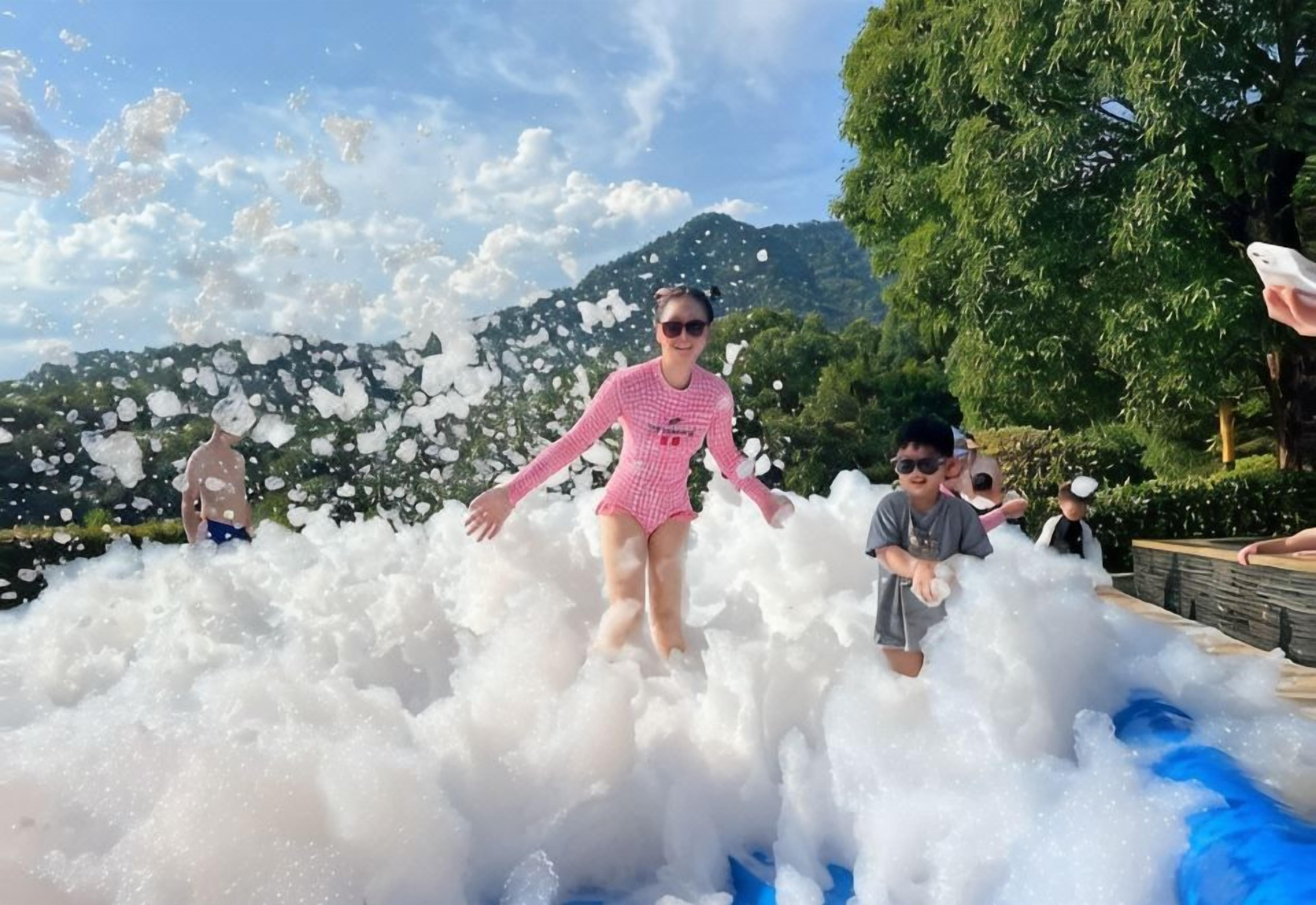 A person in a pink swimsuit playing in a large foam-filled area.