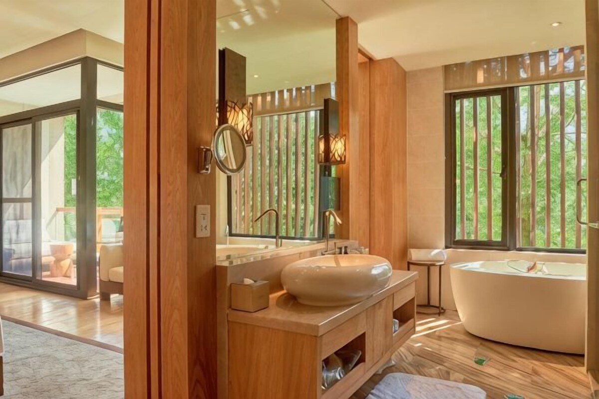 Un baño moderno con una bañera independiente, un espejo grande y un tocador con lavabo.