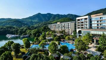 Ein Hotel mit Pool, umgeben von üppiger Vegetation und Bergen.