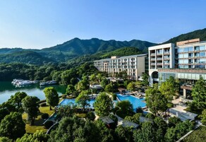 Un hotel con piscina, rodeado de exuberante vegetación y montañas.