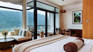 Ein Hotelzimmer mit einem großen Bett, einer Sitzecke, einem Schreibtisch und Blick ins Freie.